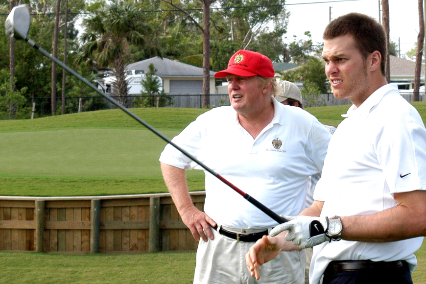 American football player Tom Brady (fore) tees off, watched by real estate developer Donald Trump (in red cap), on the course at Trump International Golf Club, Palm Beach, Florida, January 22, 2006. (Photo by Davidoff Studios/Getty Images)